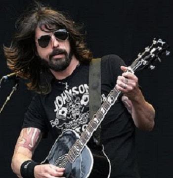 In the photo is shown Dave Grohl, he's wearing sunglasses and holding a guitar